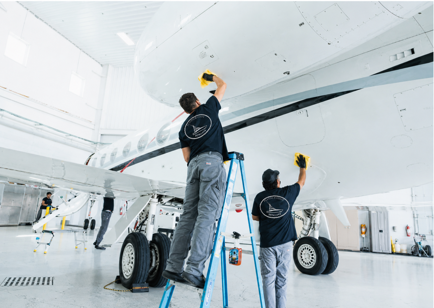 Platinum Coast technicians applying ceramic detail to the underside of a private jet in a Naples, Florida hangar