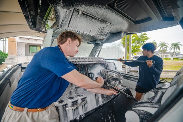 Two Platinum Coast technicians washing a center console boat in Naples, Florida