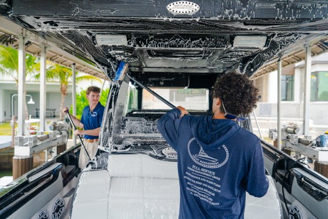Platinum Coast Detailers technicians foam-washing a yacht hardtop at a Naples, Florida marina